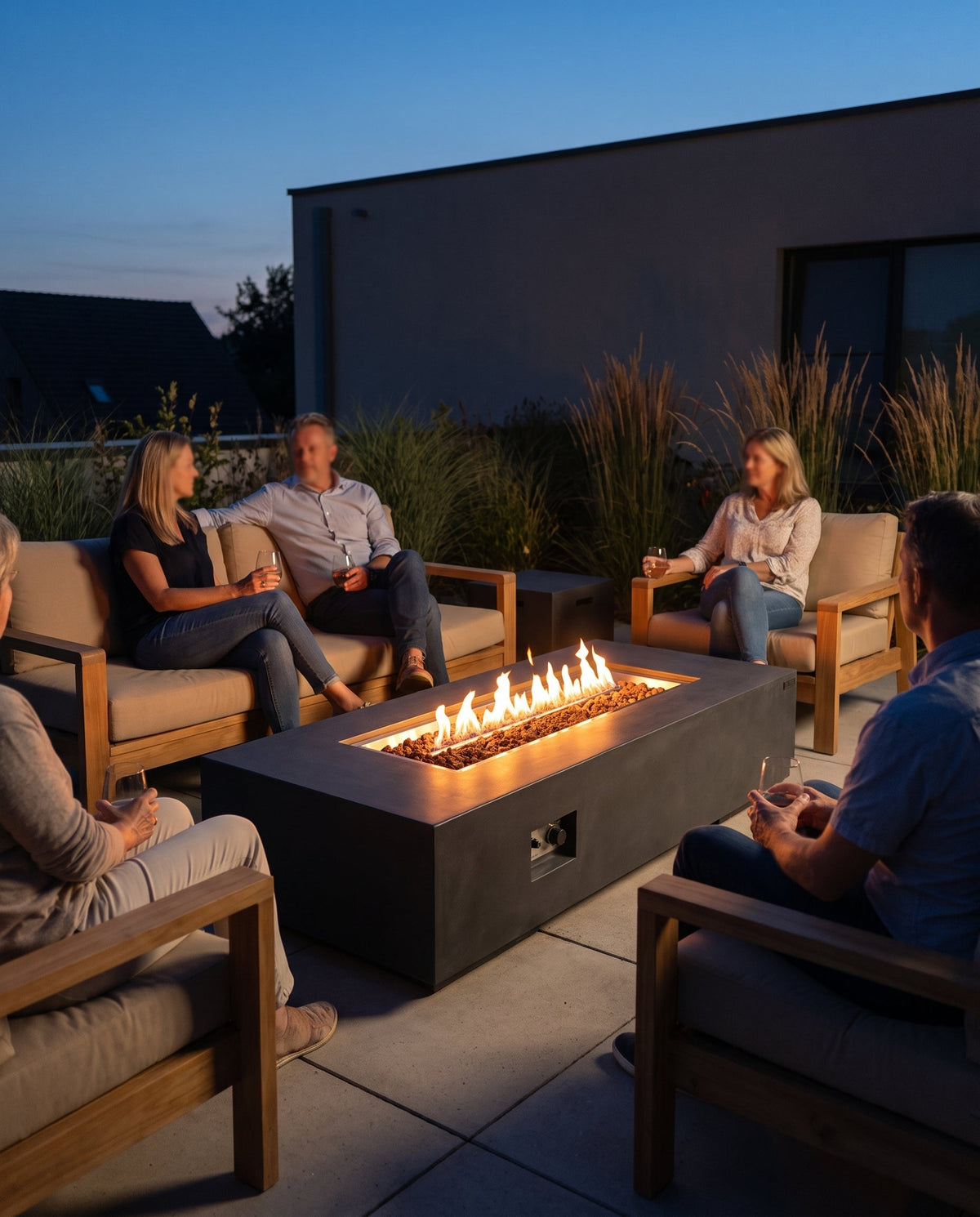 Gas-Feuertisch als Mittelpunkt einer Lounge-Sitzgruppe auf der Terrasse am Abend
