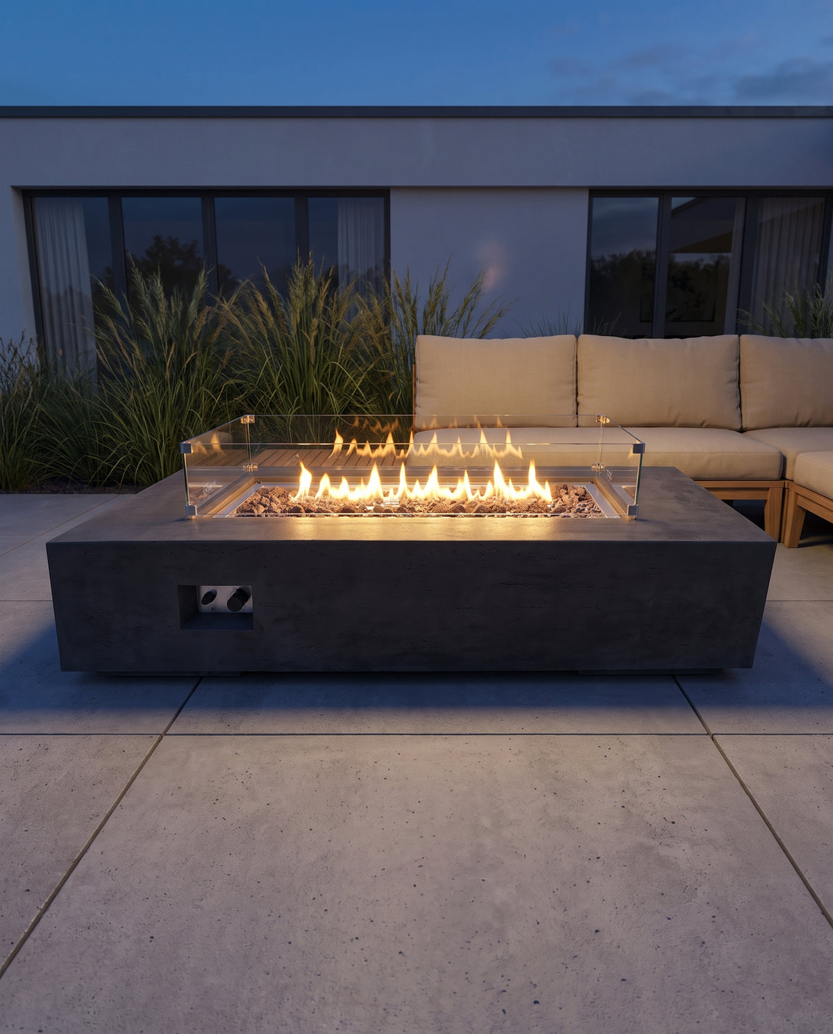 Monolith LX Gas-Feuertisch mit Glaswindschutz und brennendem Flammenband auf einer Terrasse zur blauen Stunde